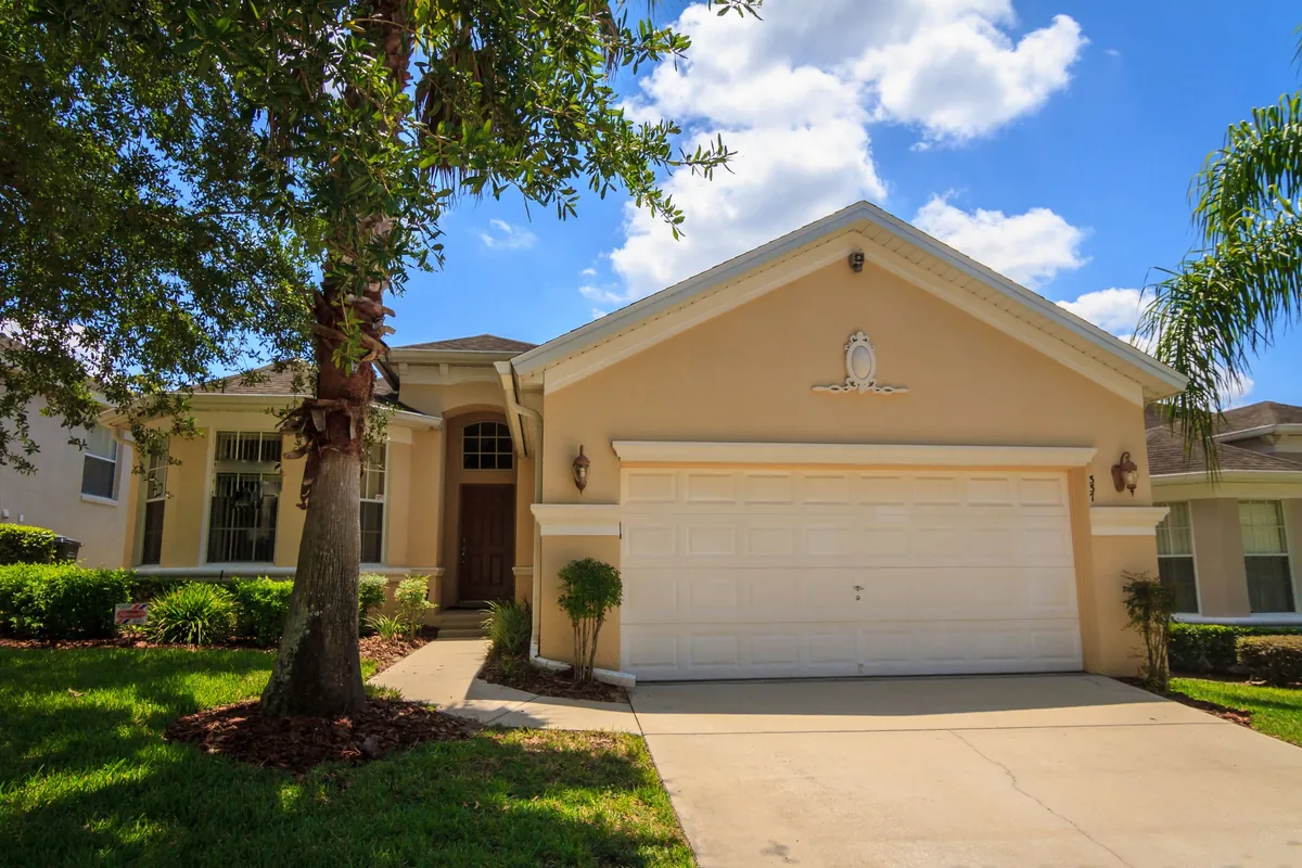 Single-story stucco home with a two-car garage, palm and green lawn
