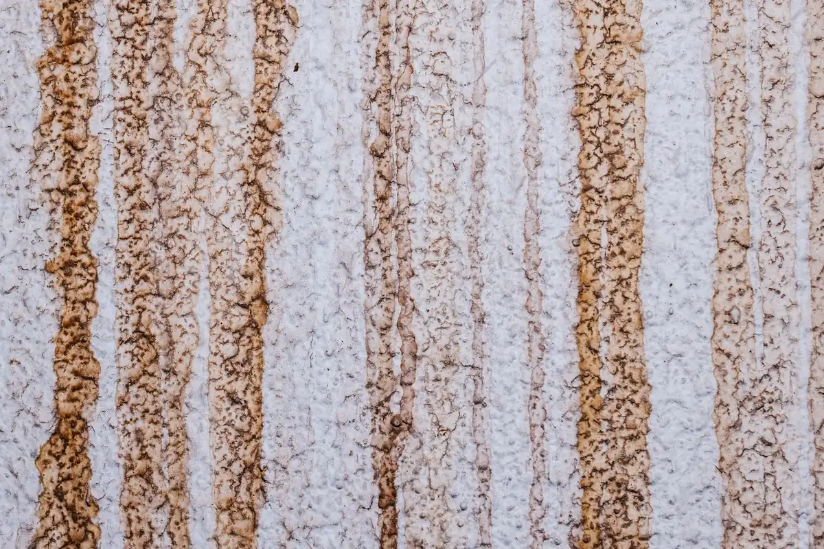 Orange rust streaks running down a white wall
